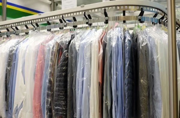 Cleaned shirts in plastic garment bags hanging on a rack at a dry cleaner.