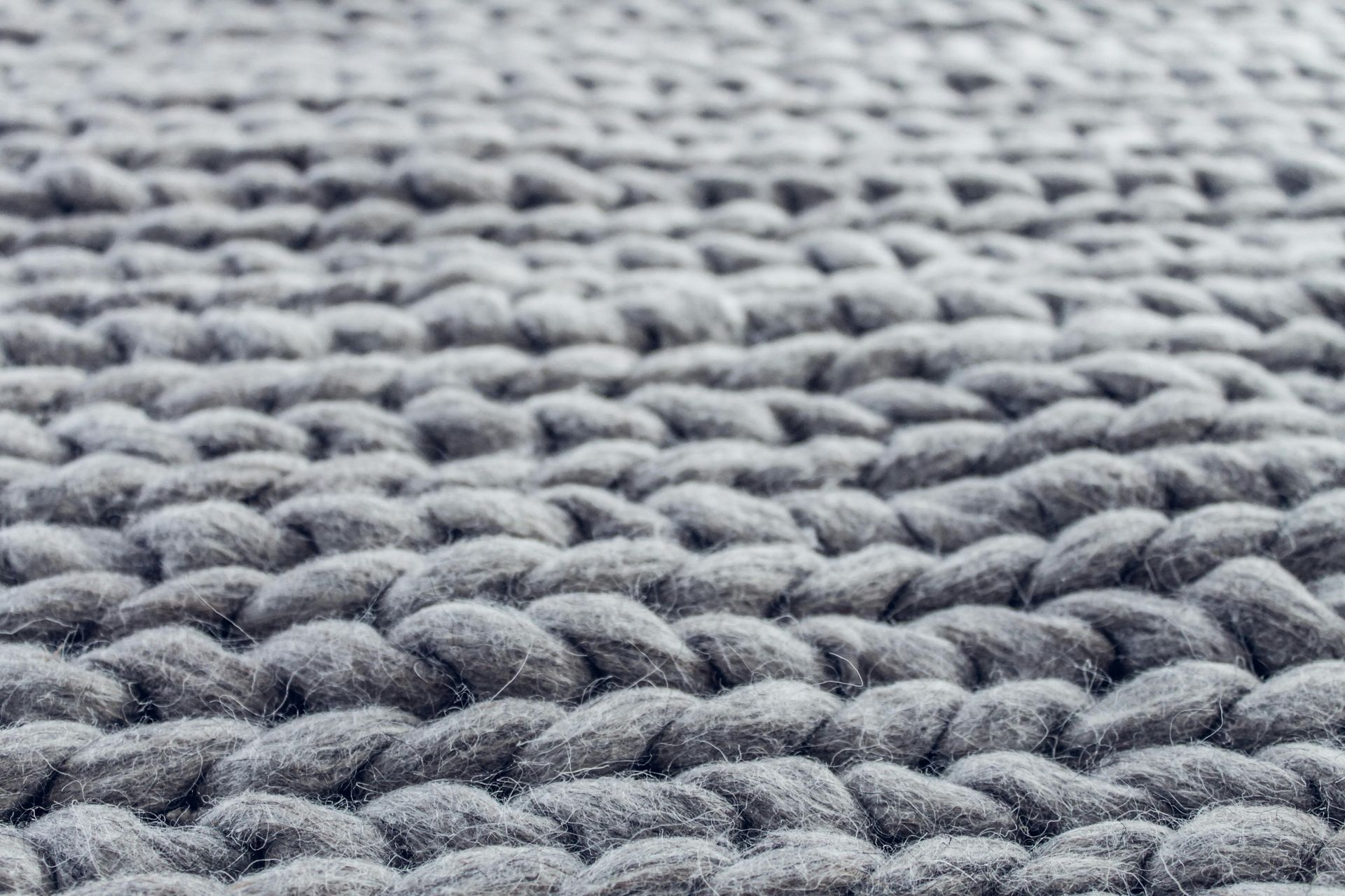 Close-up view of gray, chunky-knit fabric, showing thick, textured loops.