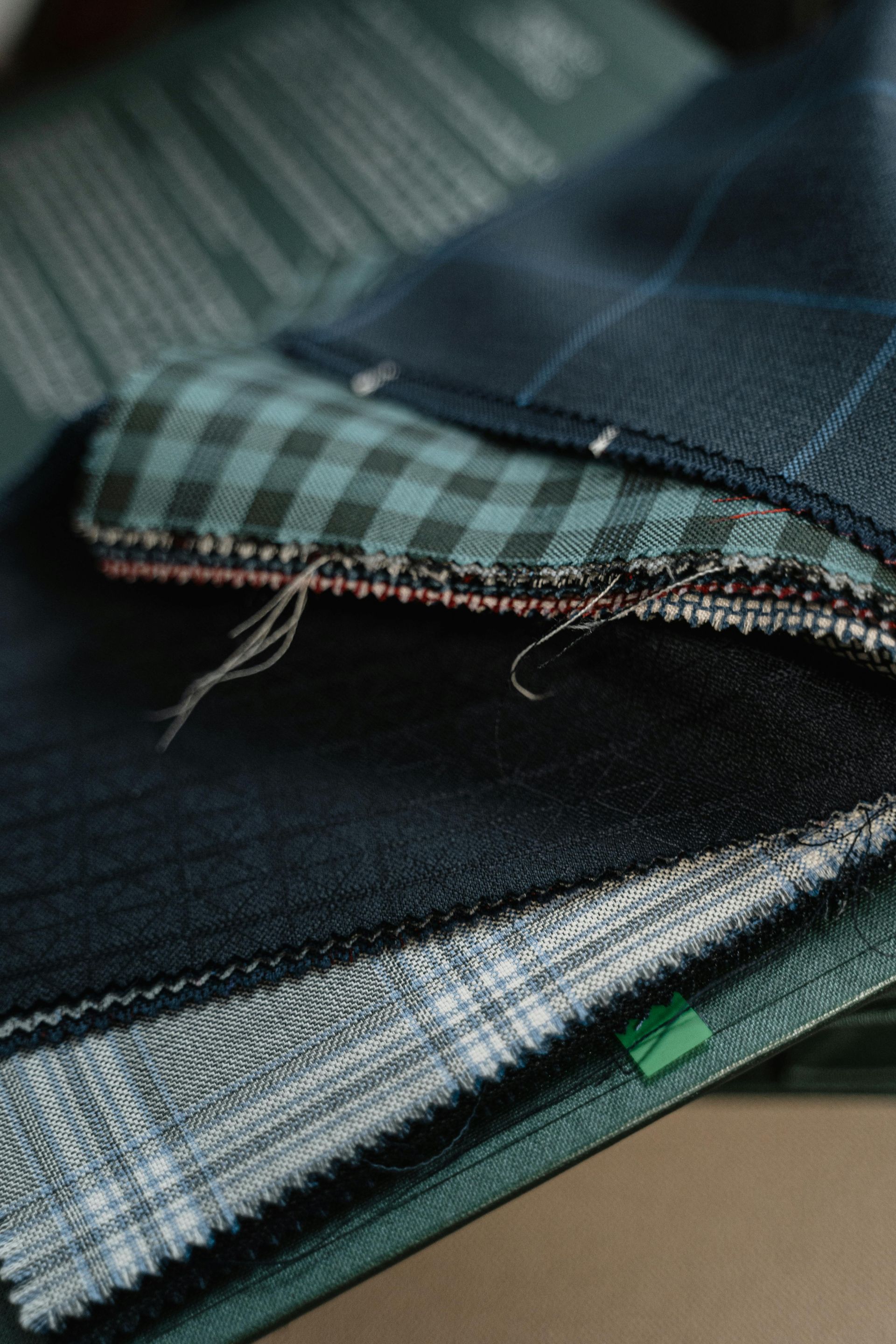 Close-up of fabric swatches in various shades of blue and green, featuring plaid and check patterns.