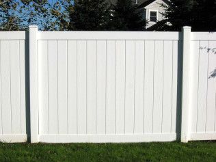 White vinyl privacy fence in a grassy yard.