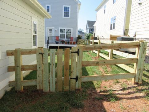 A wooden fence and gate in a backyard, with a house in the background.