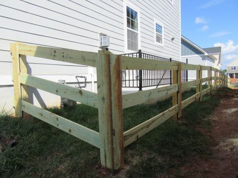 Wooden split-rail fence alongside a light-colored building.