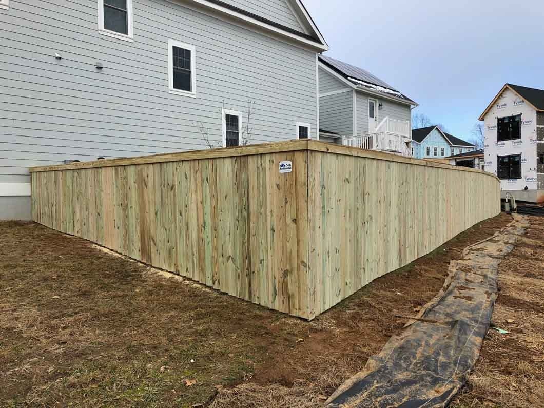 Wooden privacy fence surrounding a property with newly constructed houses in the background.