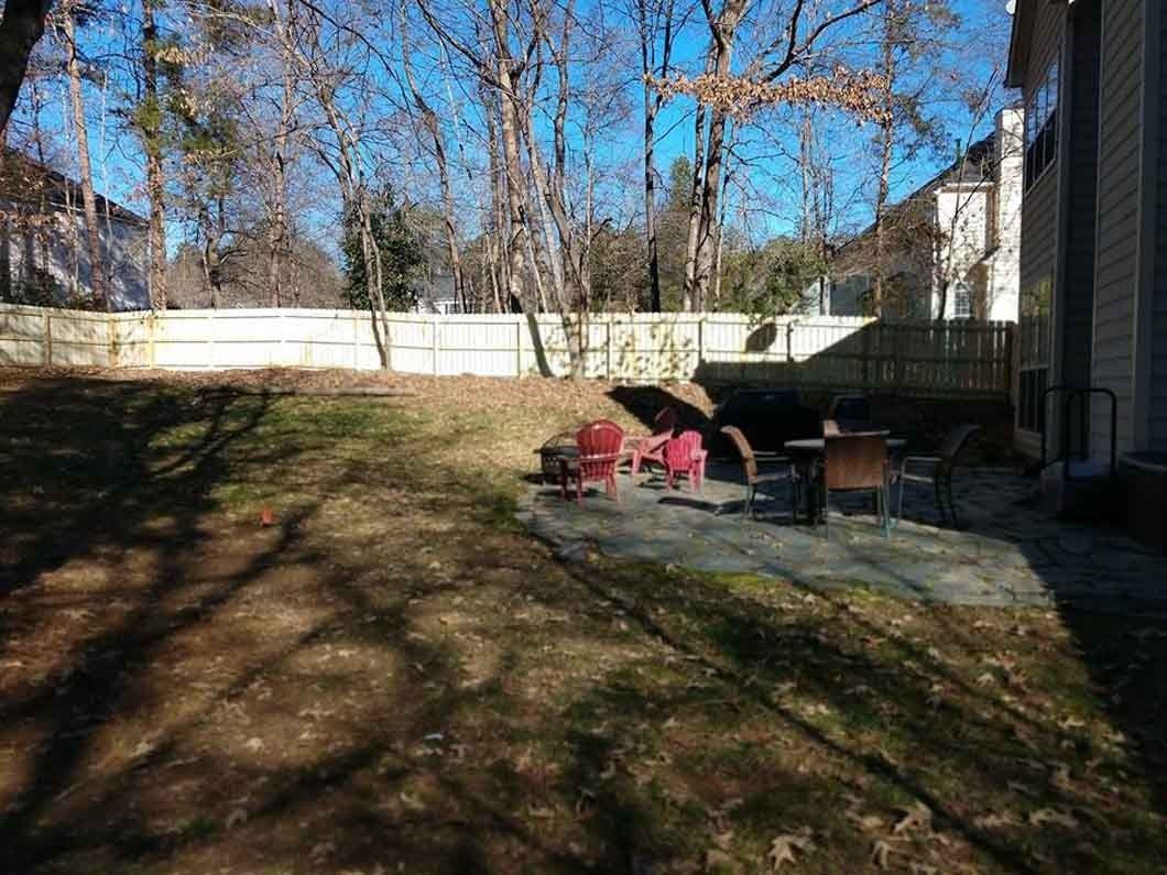 Backyard with a small patio, fire pit, and several chairs; sunny day.