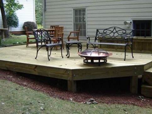 Wooden deck with patio furniture and a fire pit in a backyard setting.