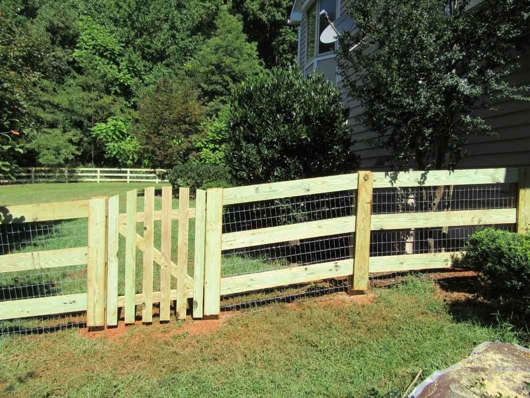 Wooden fence with gate in a yard; trees and a house in the background.