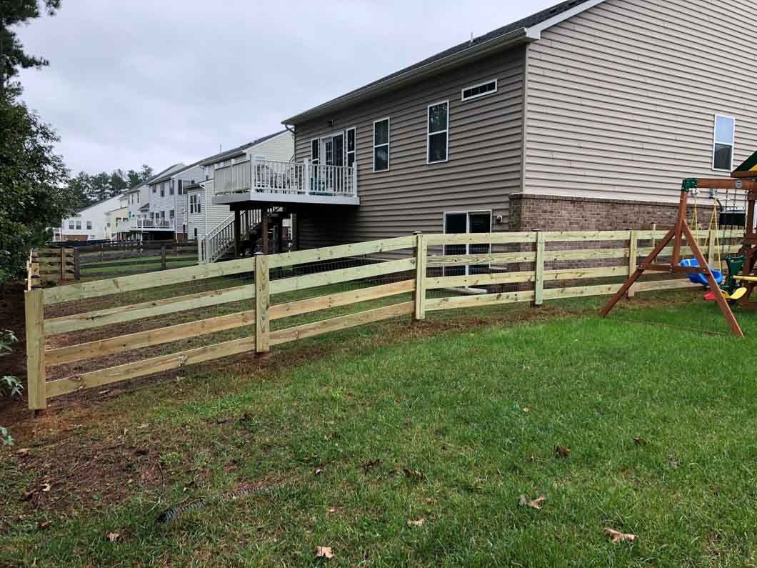 Wooden fence in a backyard, beside a house, and a playground.