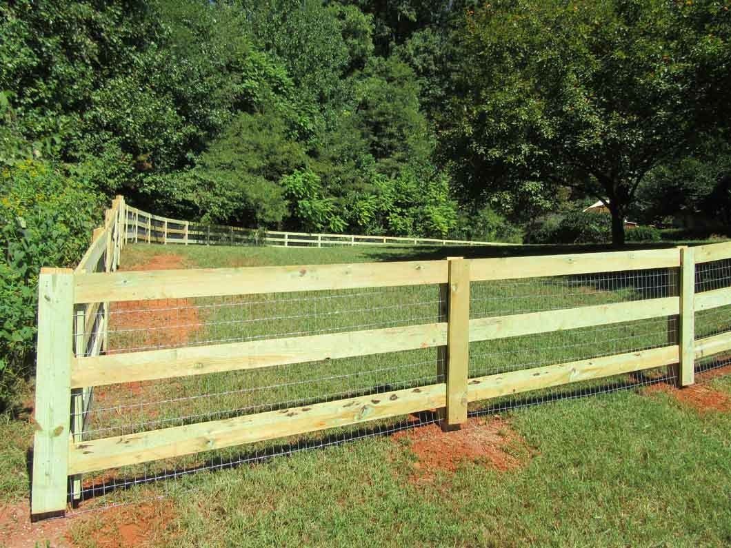 Wooden fence in a grassy yard, with trees in the background.