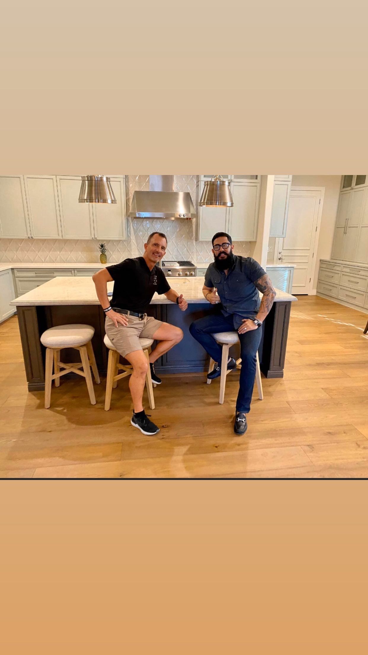 Two men are sitting on stools in a kitchen.
