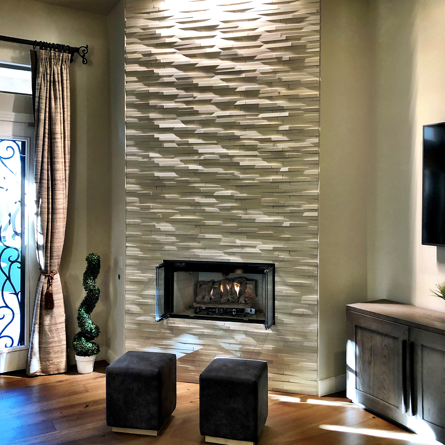 A living room with a fireplace and two ottomans