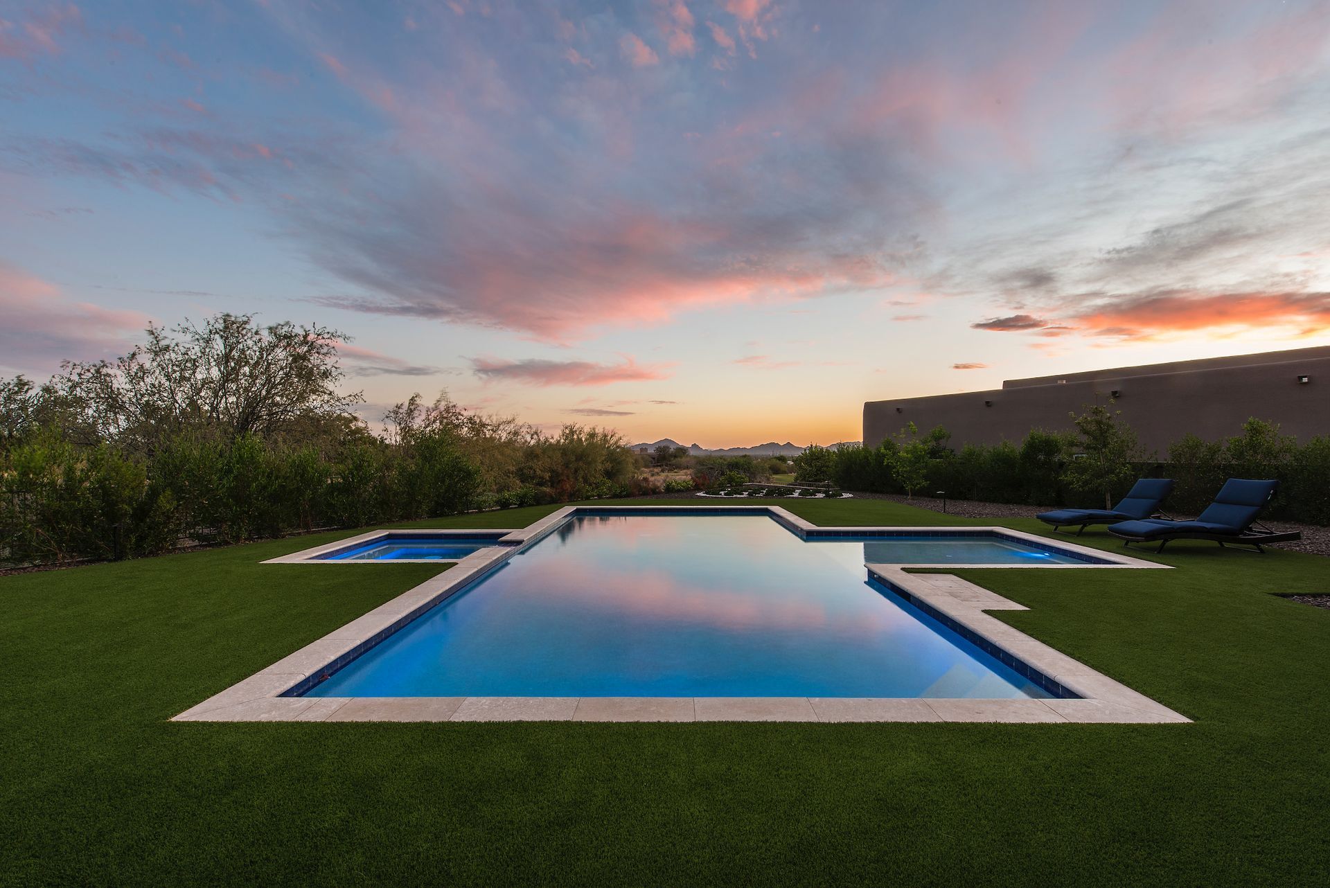 There is a large swimming pool in the middle of a lush green field.