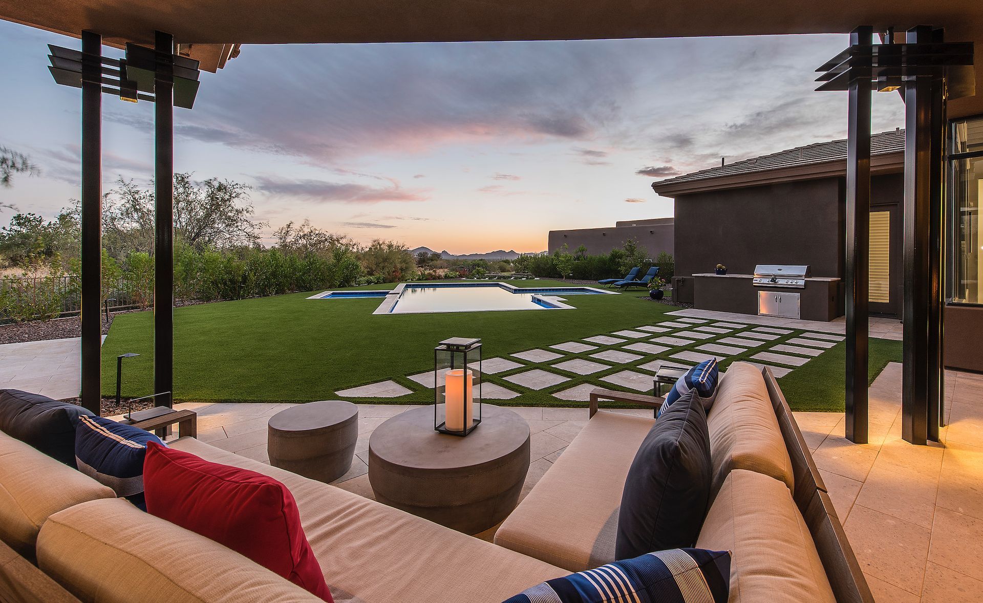 A patio with a couch and a table and a pool in the background