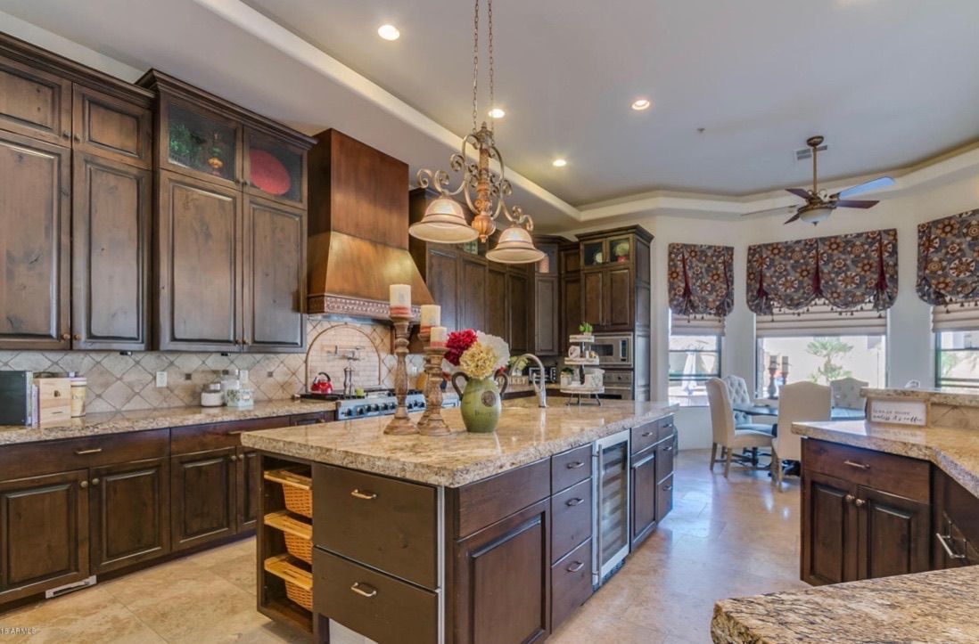 A kitchen with a large island , granite counter tops , and wooden cabinets.