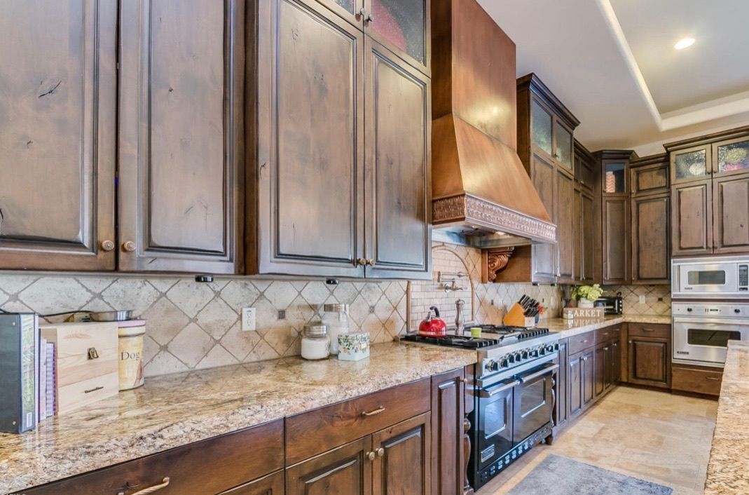 A kitchen with wooden cabinets , granite counter tops , and a stove.