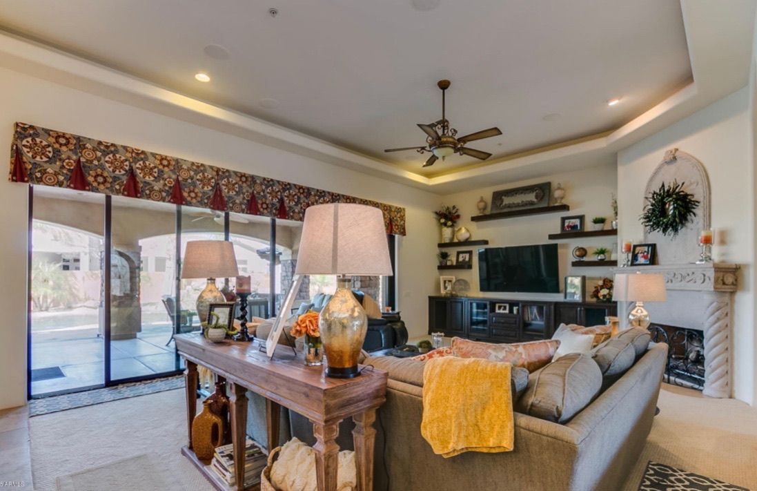 A living room with a couch , table , lamps , television and fireplace.