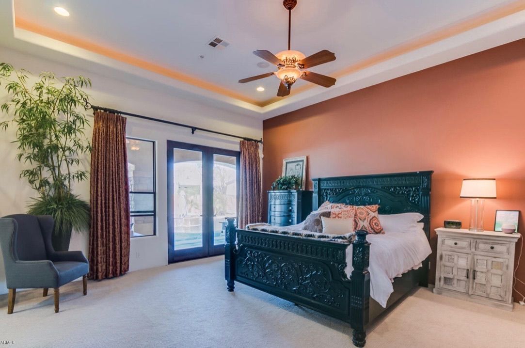 A bedroom with a bed , chair , nightstand and ceiling fan.