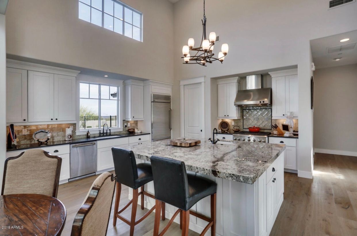 A kitchen with a large island and a chandelier hanging from the ceiling.