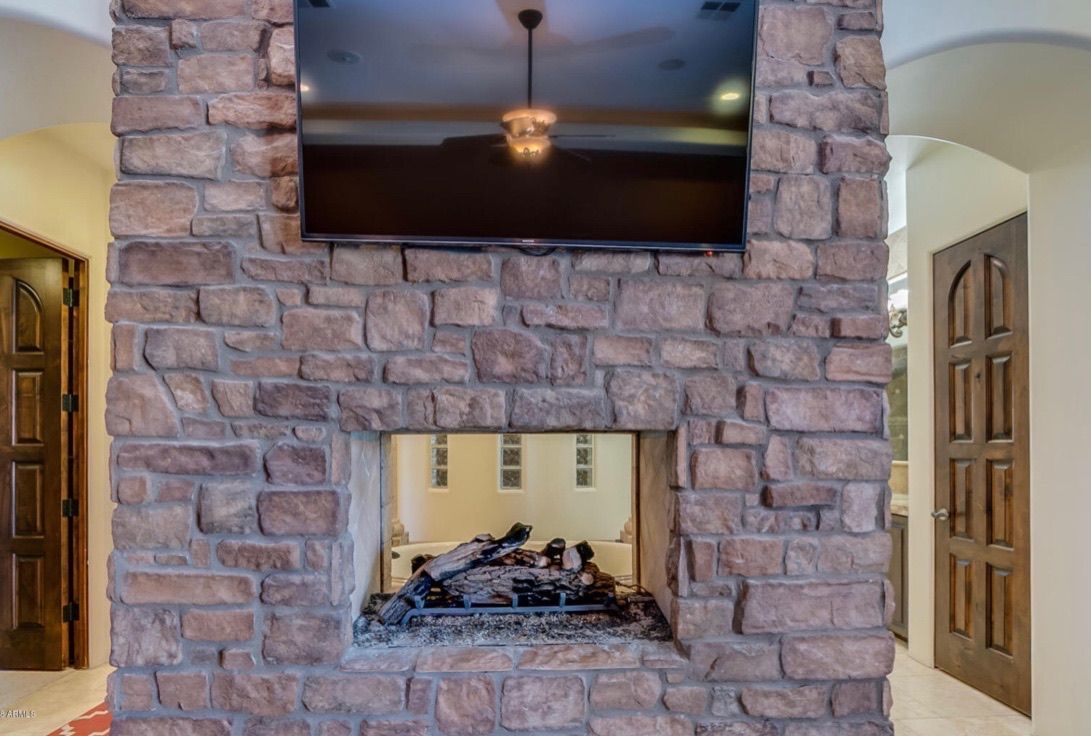 A brick fireplace with a flat screen tv above it.
