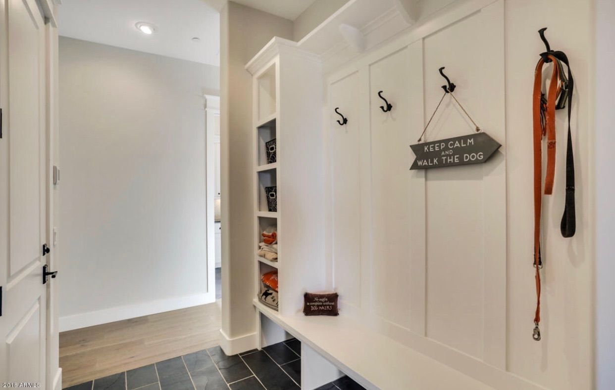 A dog leash is hanging on a hook in a hallway.