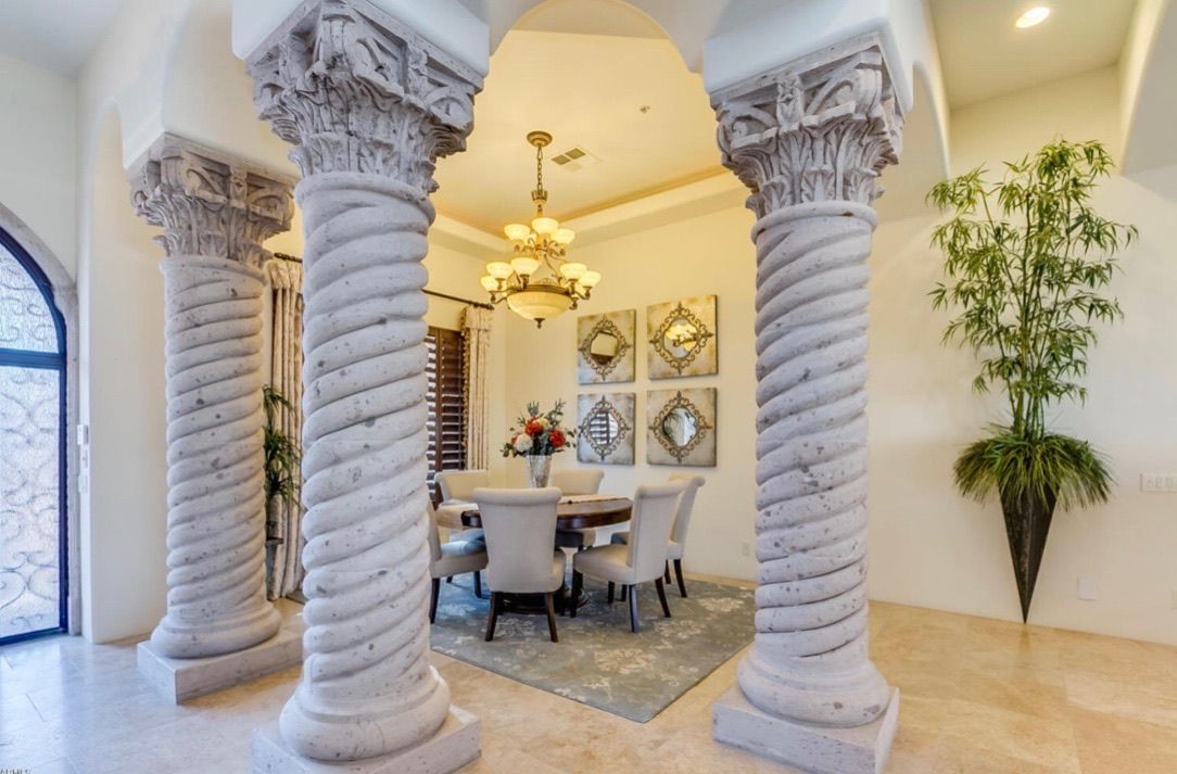 A dining room with columns and a table and chairs