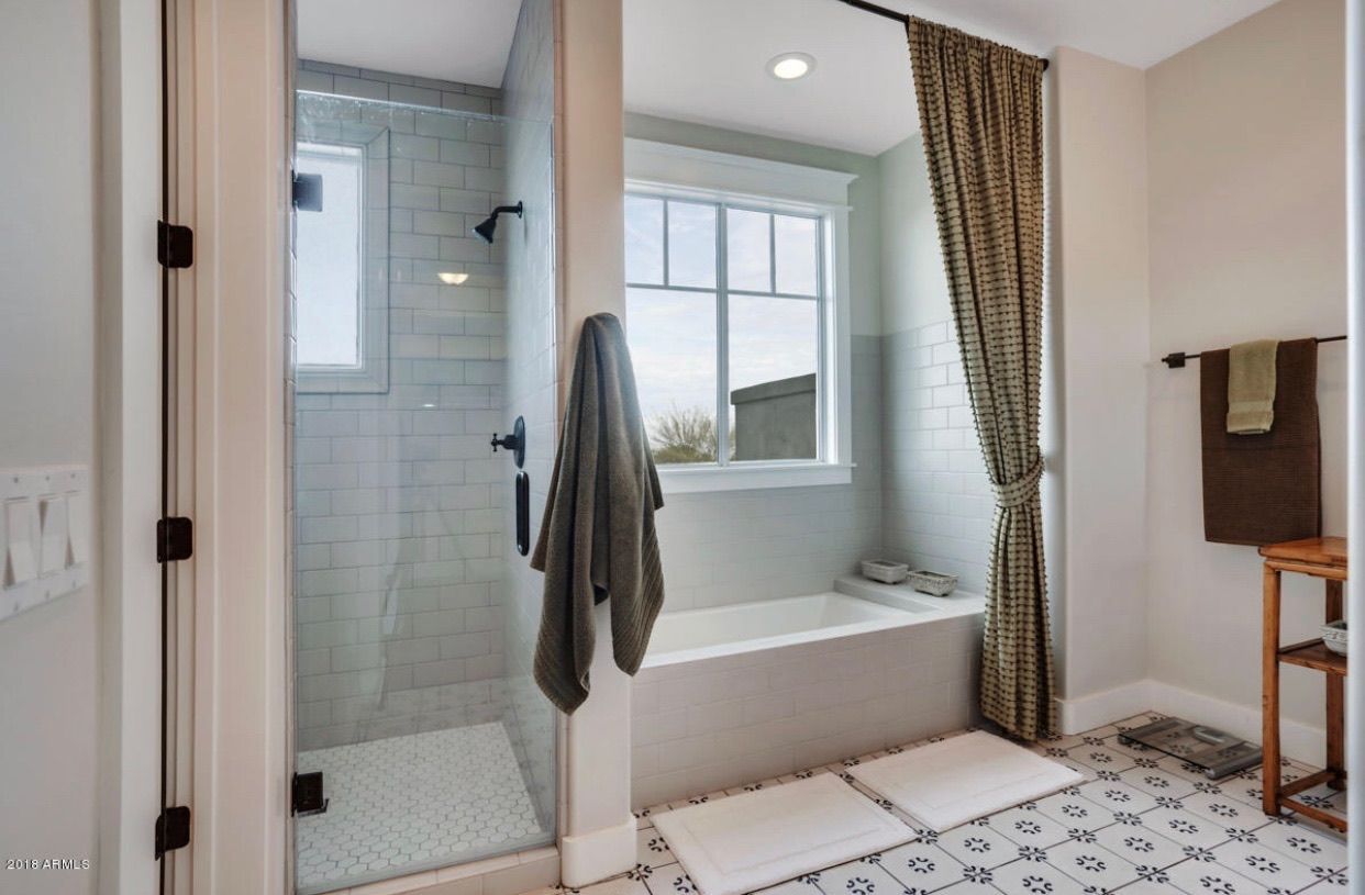 A bathroom with a tub , shower , and window.