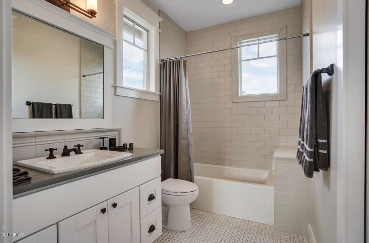 A bathroom with a sink , toilet , shower and window.