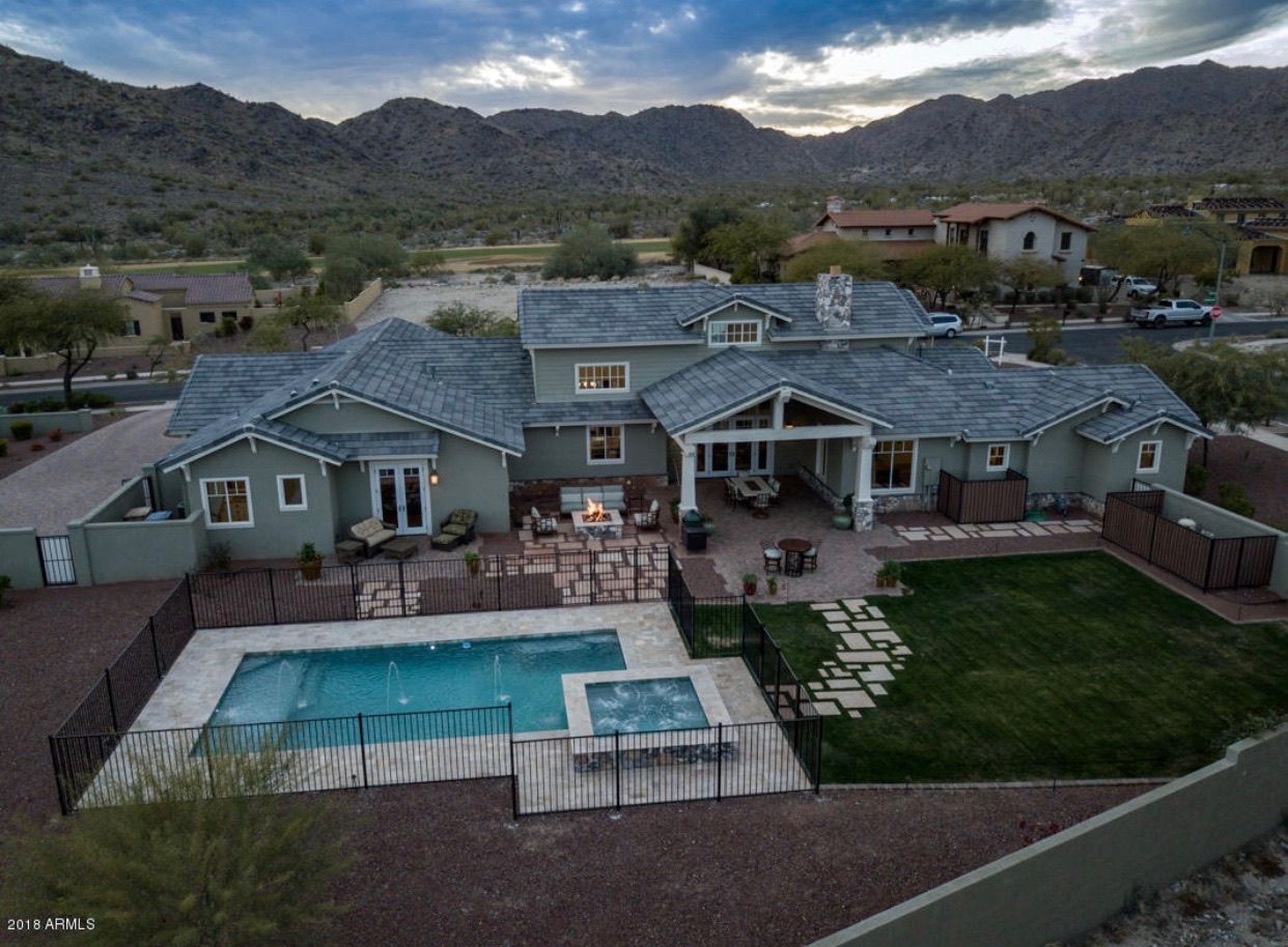 An aerial view of a large house with a swimming pool and mountains in the background.