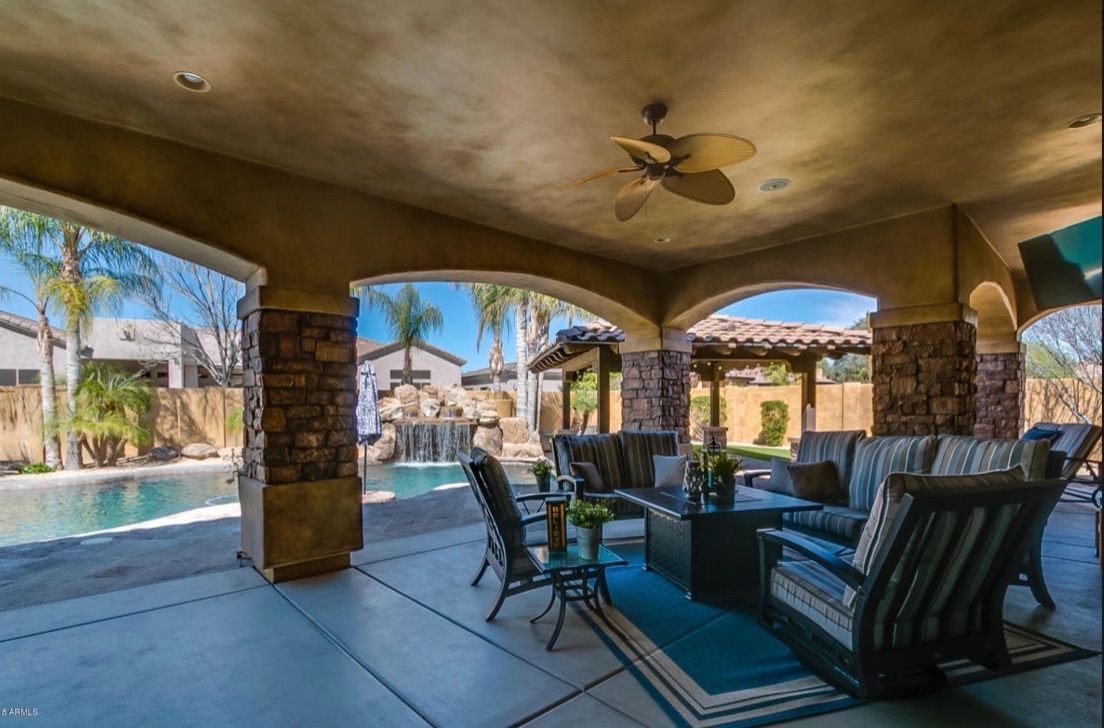 A living room with a ceiling fan and a pool in the background.