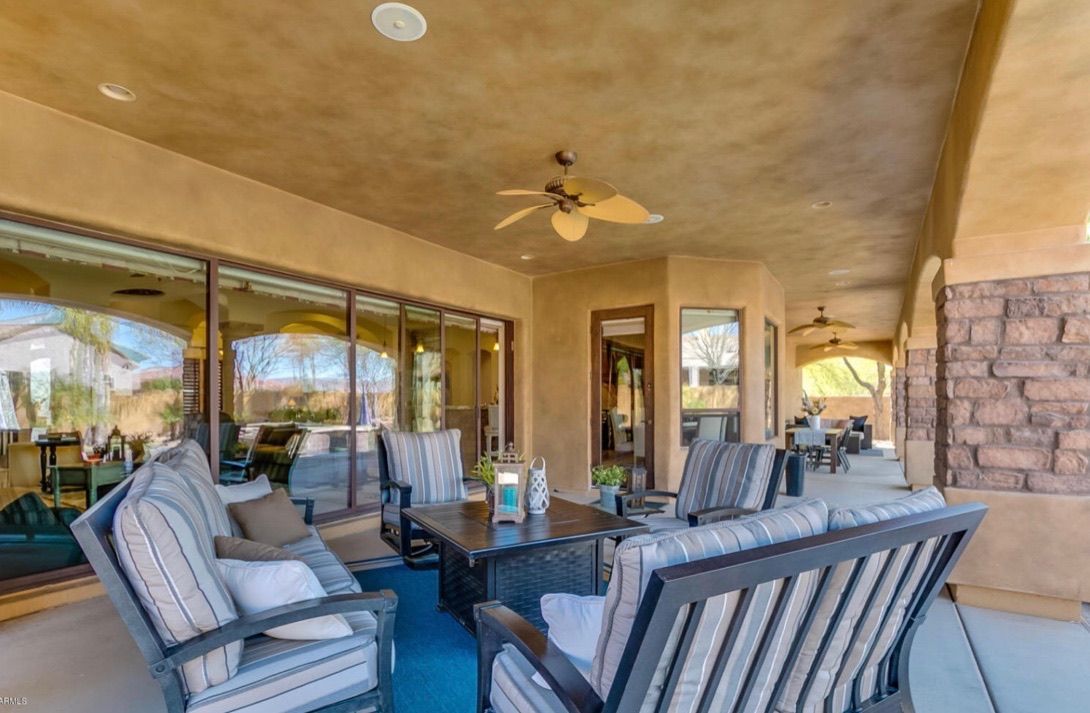 A patio with a lot of furniture and a ceiling fan.