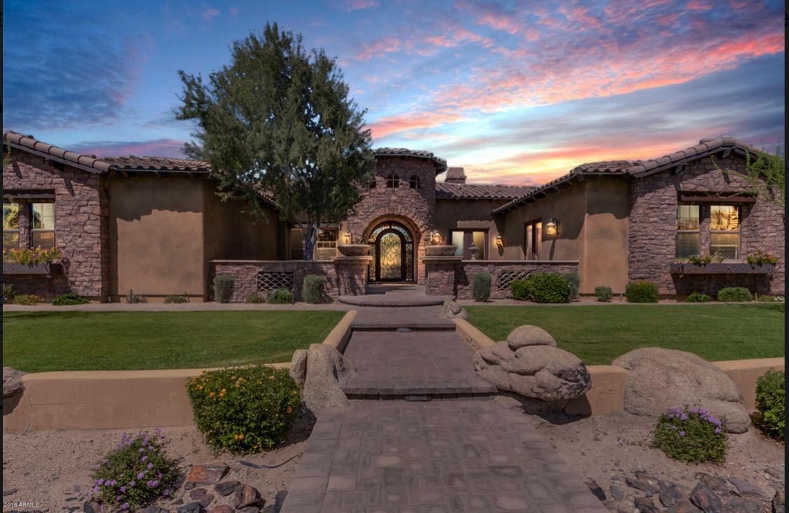 The front of a large house with a sunset in the background.