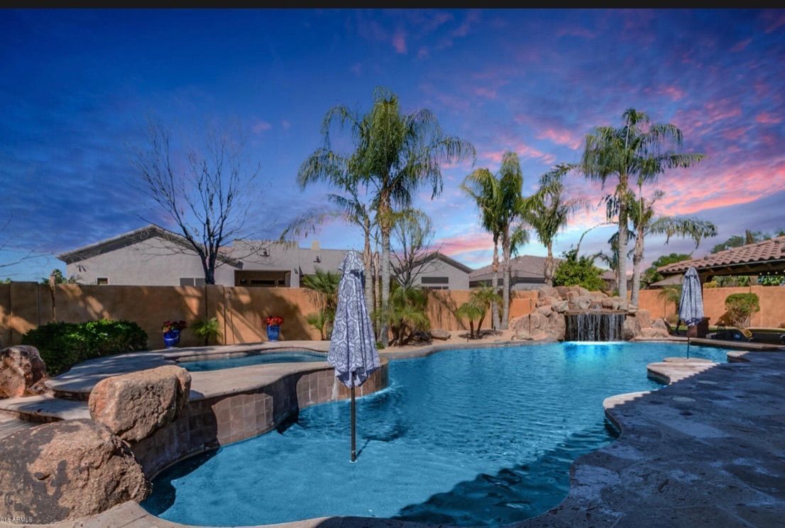 There is a large swimming pool in the backyard of a house.