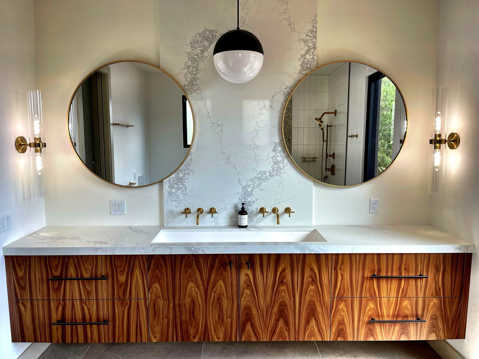 A bathroom with two sinks and two round mirrors.