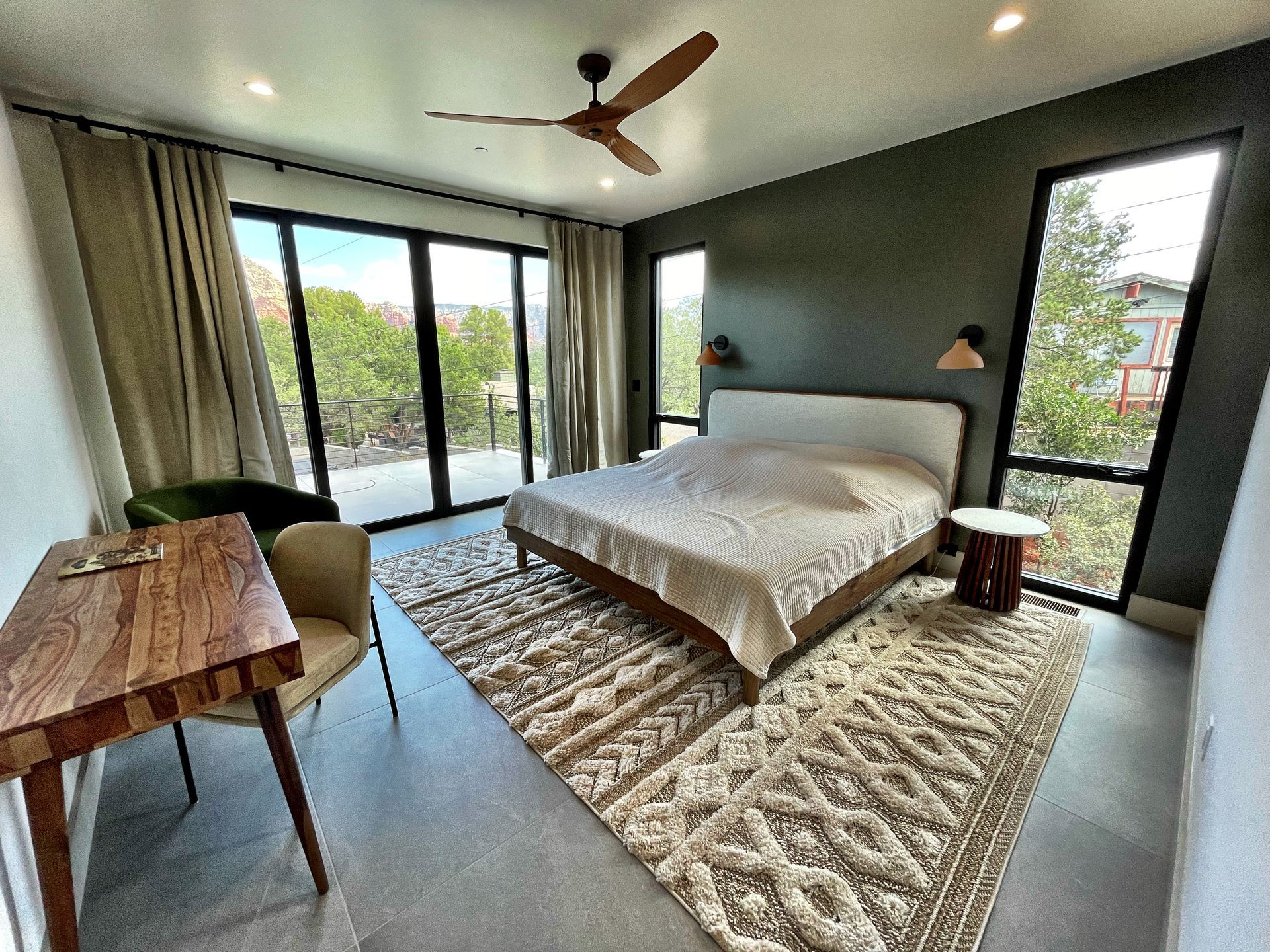 A bedroom with a large bed , desk , chair and ceiling fan.