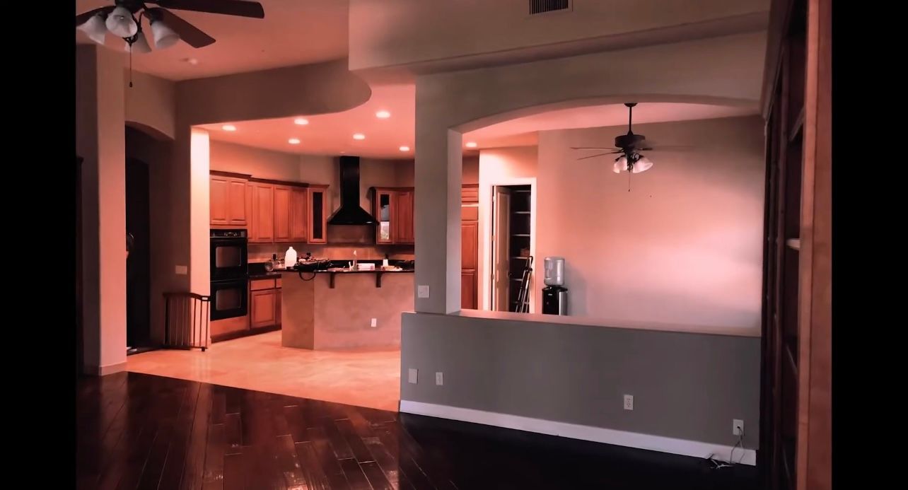 An empty house with a kitchen and a ceiling fan