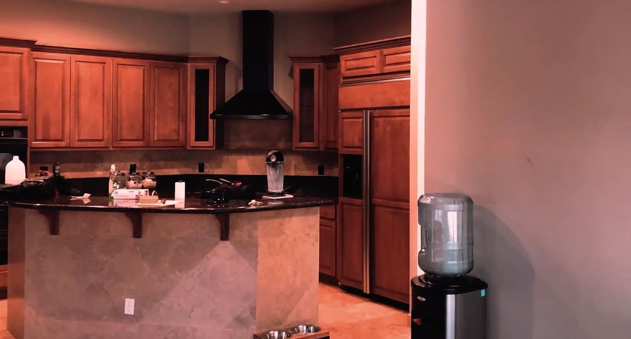 A kitchen with wooden cabinets , stainless steel appliances and a water cooler.