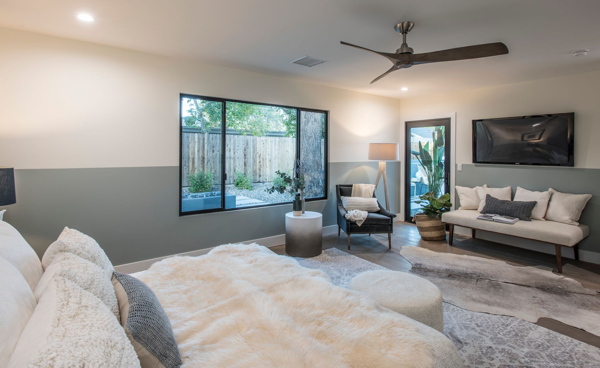 A bedroom with a bed , couch , television and ceiling fan.