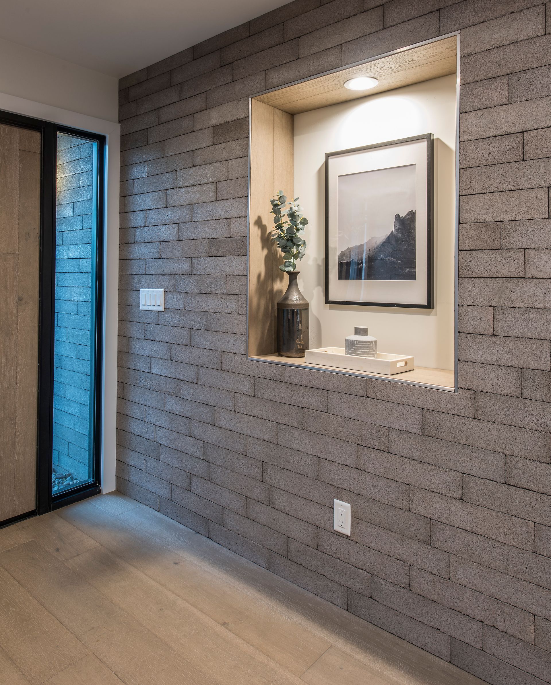 A hallway with a brick wall and a picture on the wall