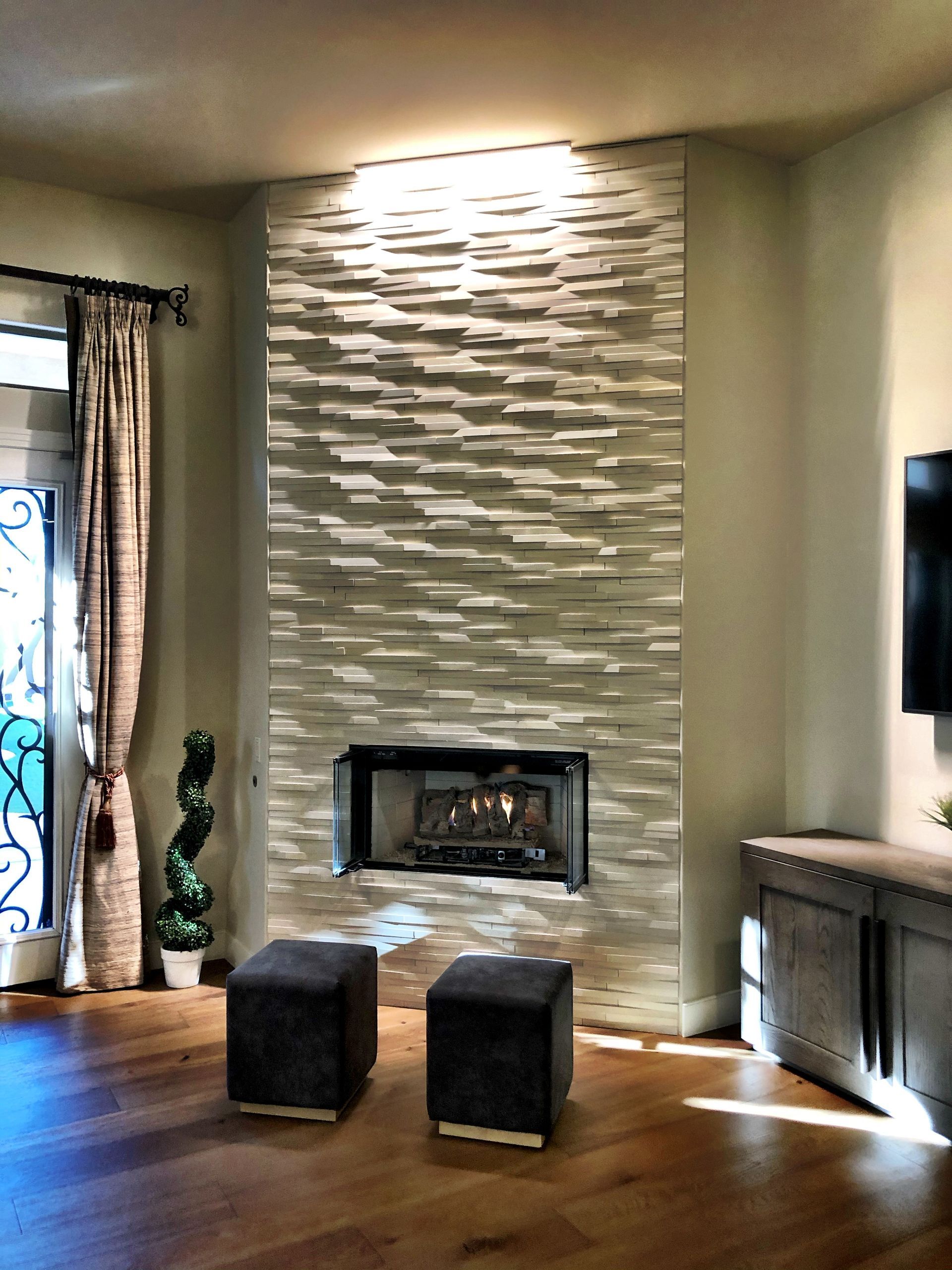 A living room with a fireplace and two ottomans