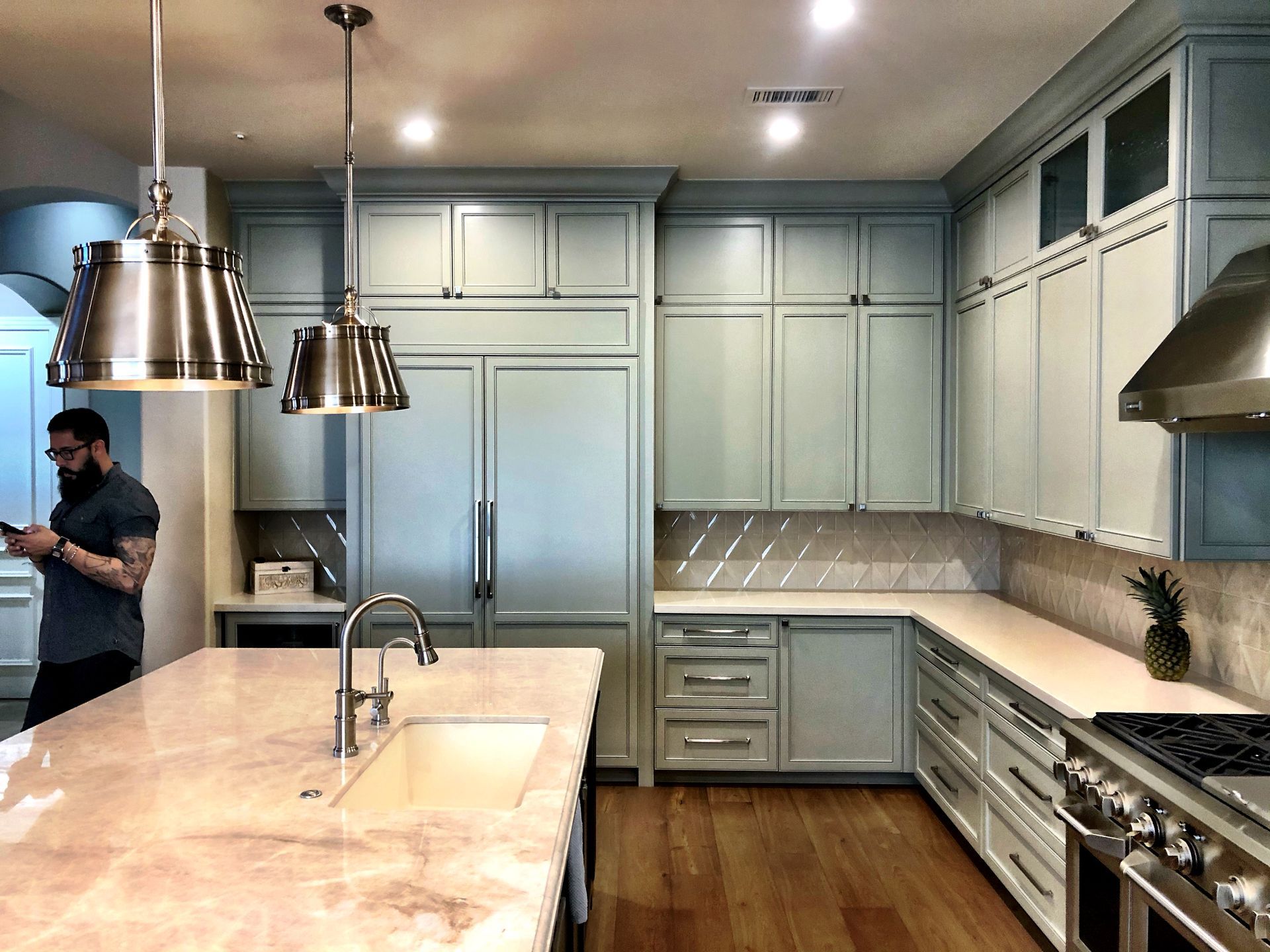 A man is standing in a kitchen looking at his phone.