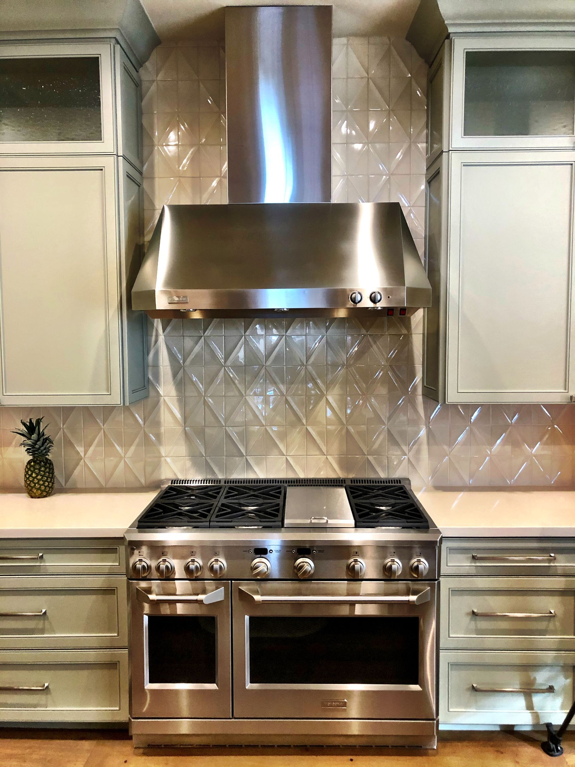 A stainless steel stove in a kitchen with white cabinets