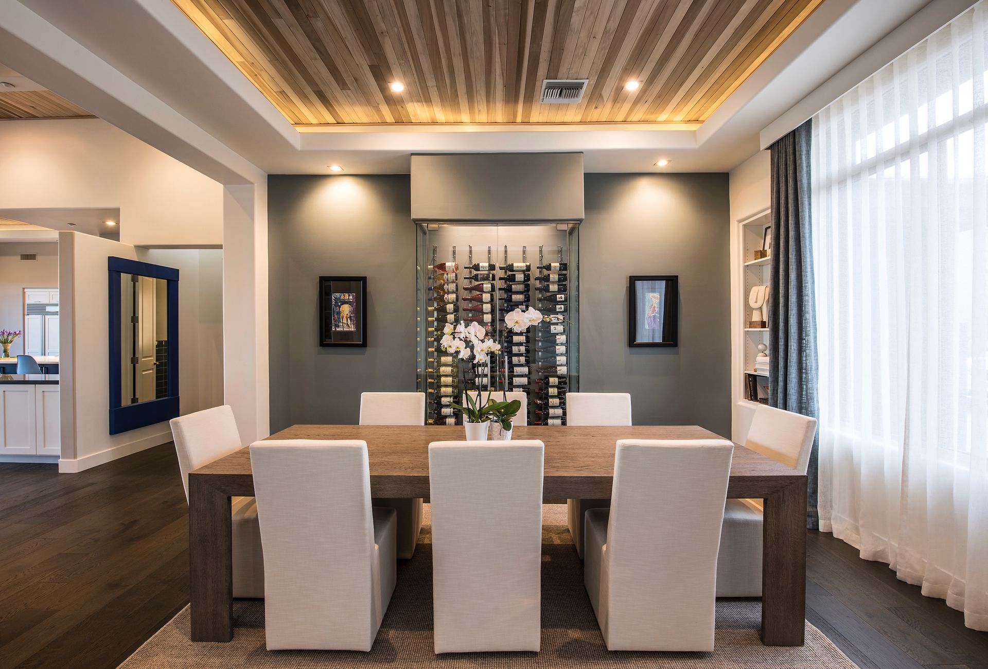 A dining room with a table and chairs and a wine rack on the wall.
