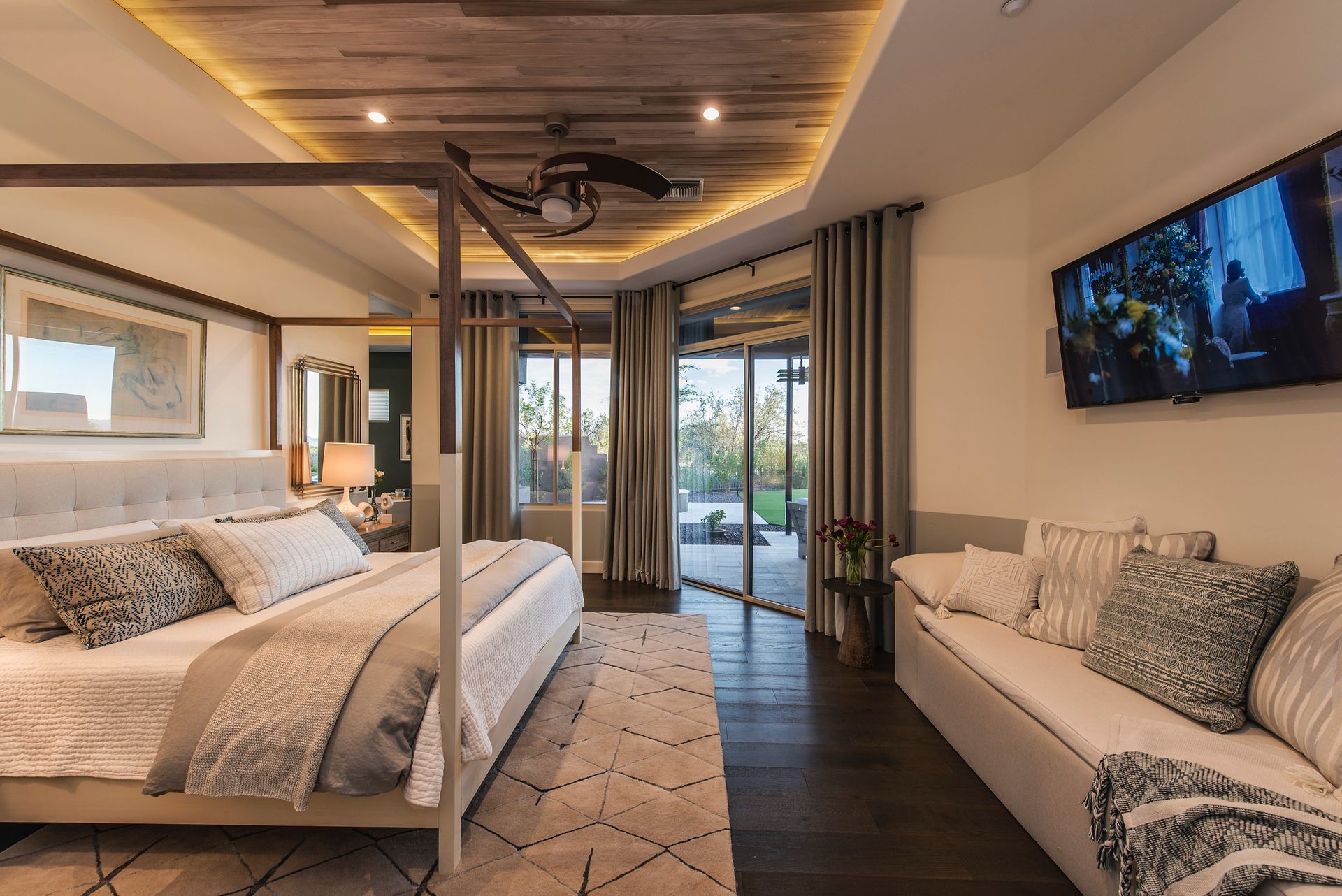 A bedroom with a canopy bed , couch , and television.