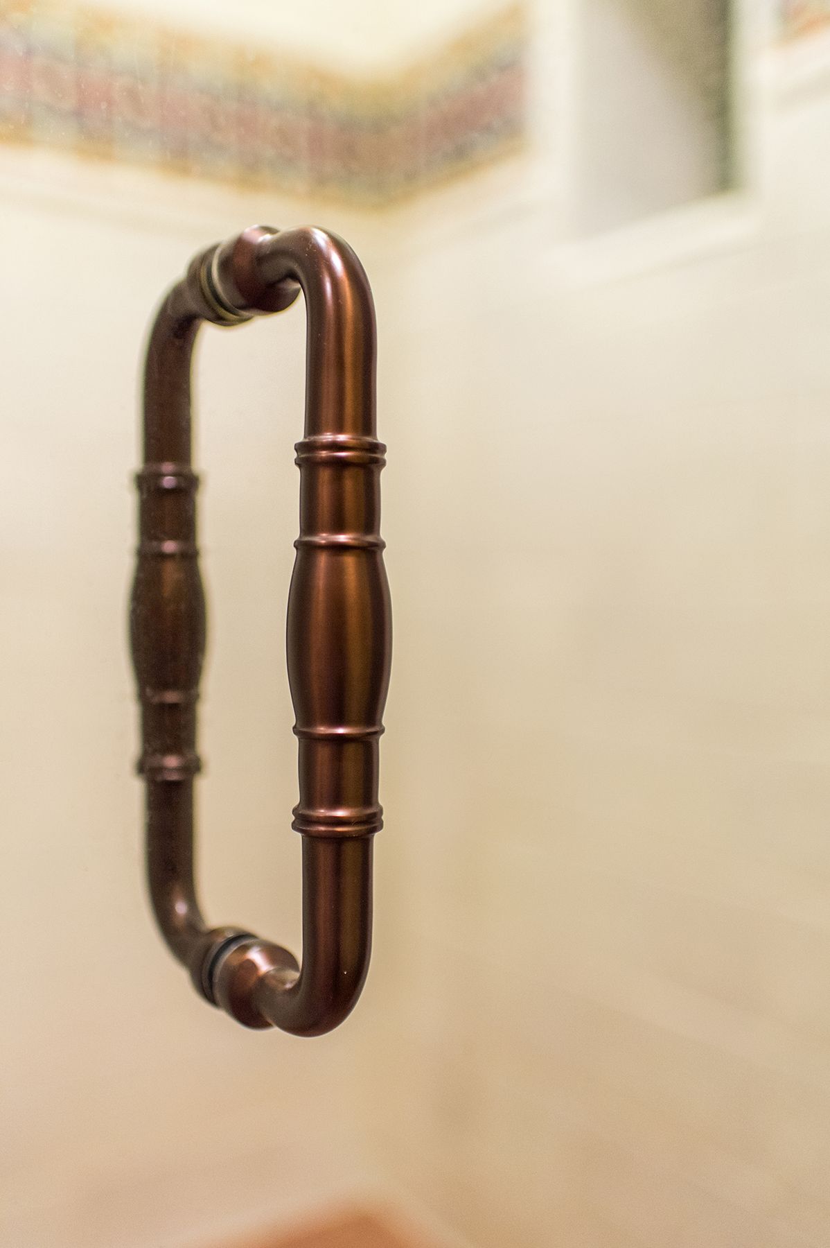 A close up of a shower door handle in a bathroom.