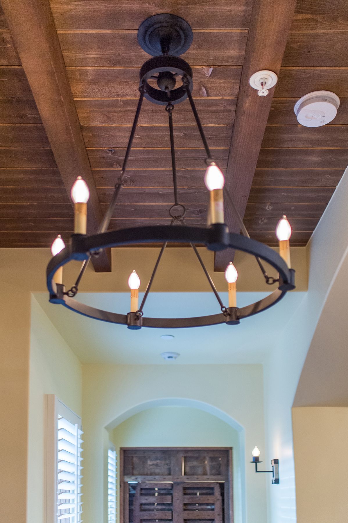 A chandelier with candles hanging from the ceiling in a hallway