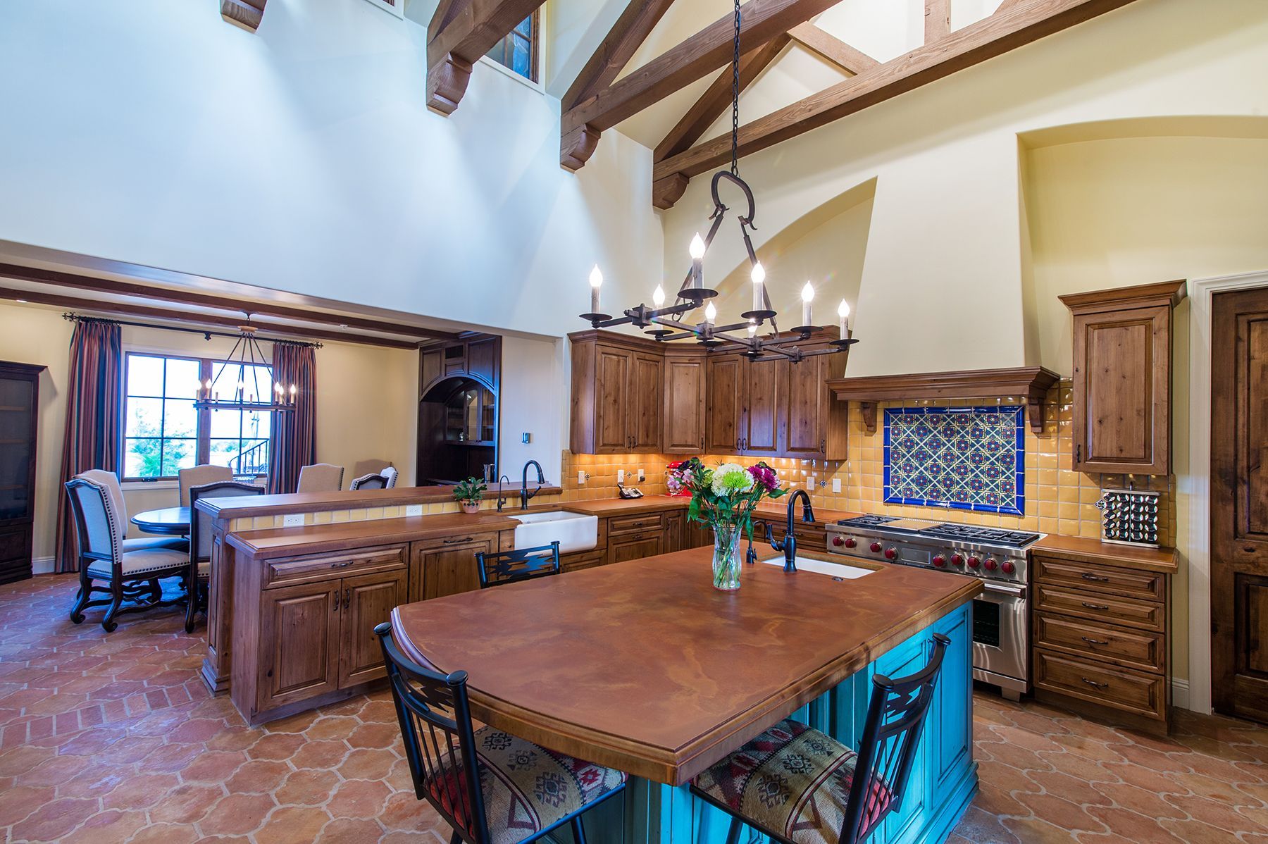 A kitchen with a large table and chairs and a chandelier hanging from the ceiling.