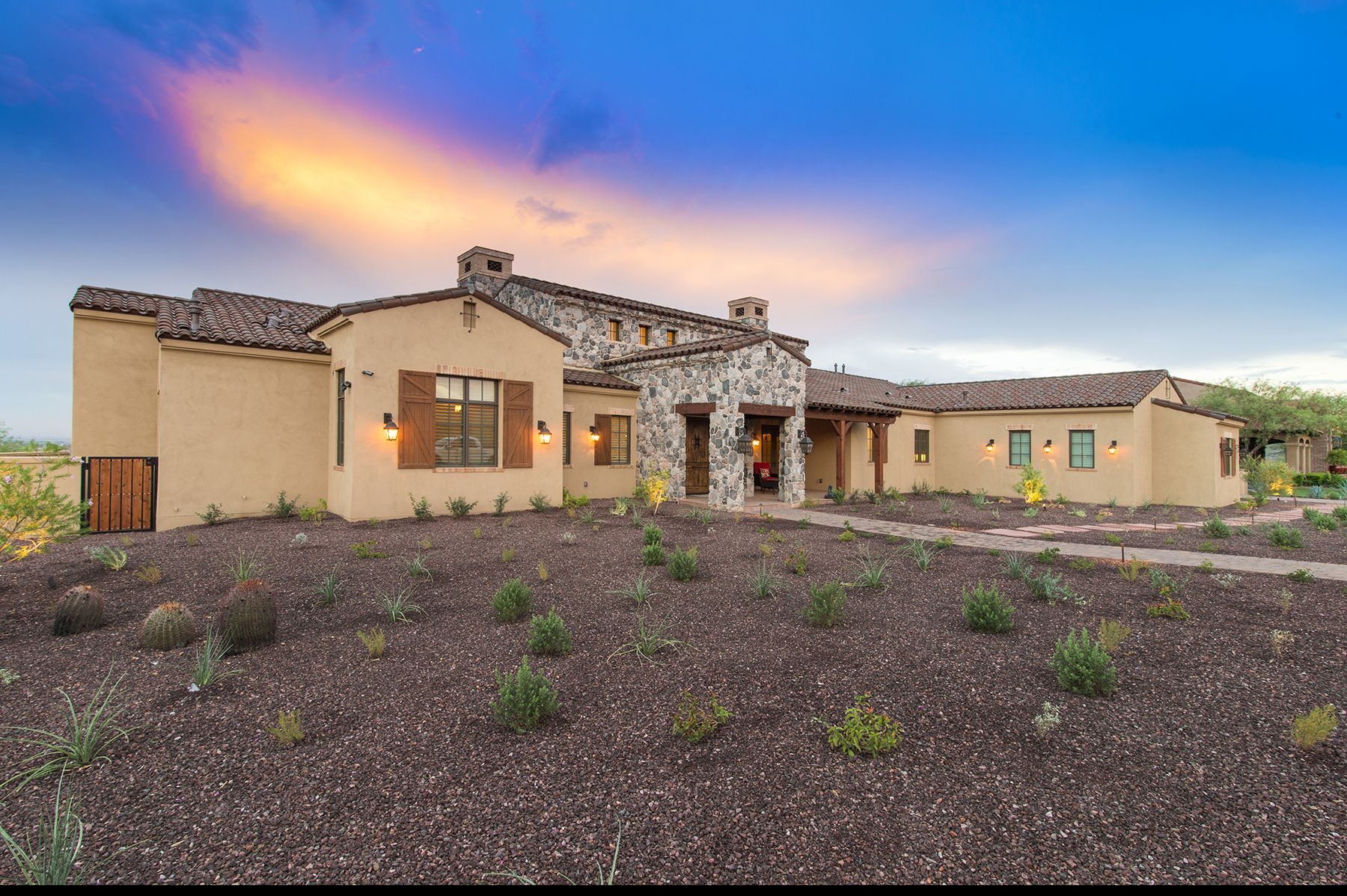 A large house is sitting in the middle of a dirt field.