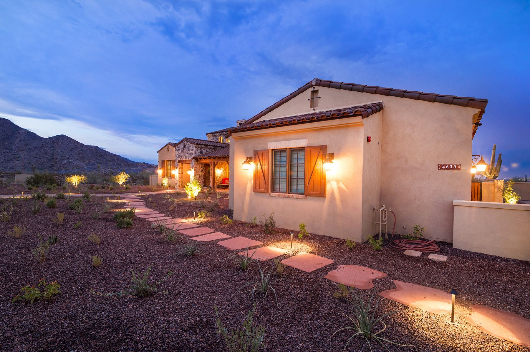 A house with a walkway leading to it is lit up at night.
