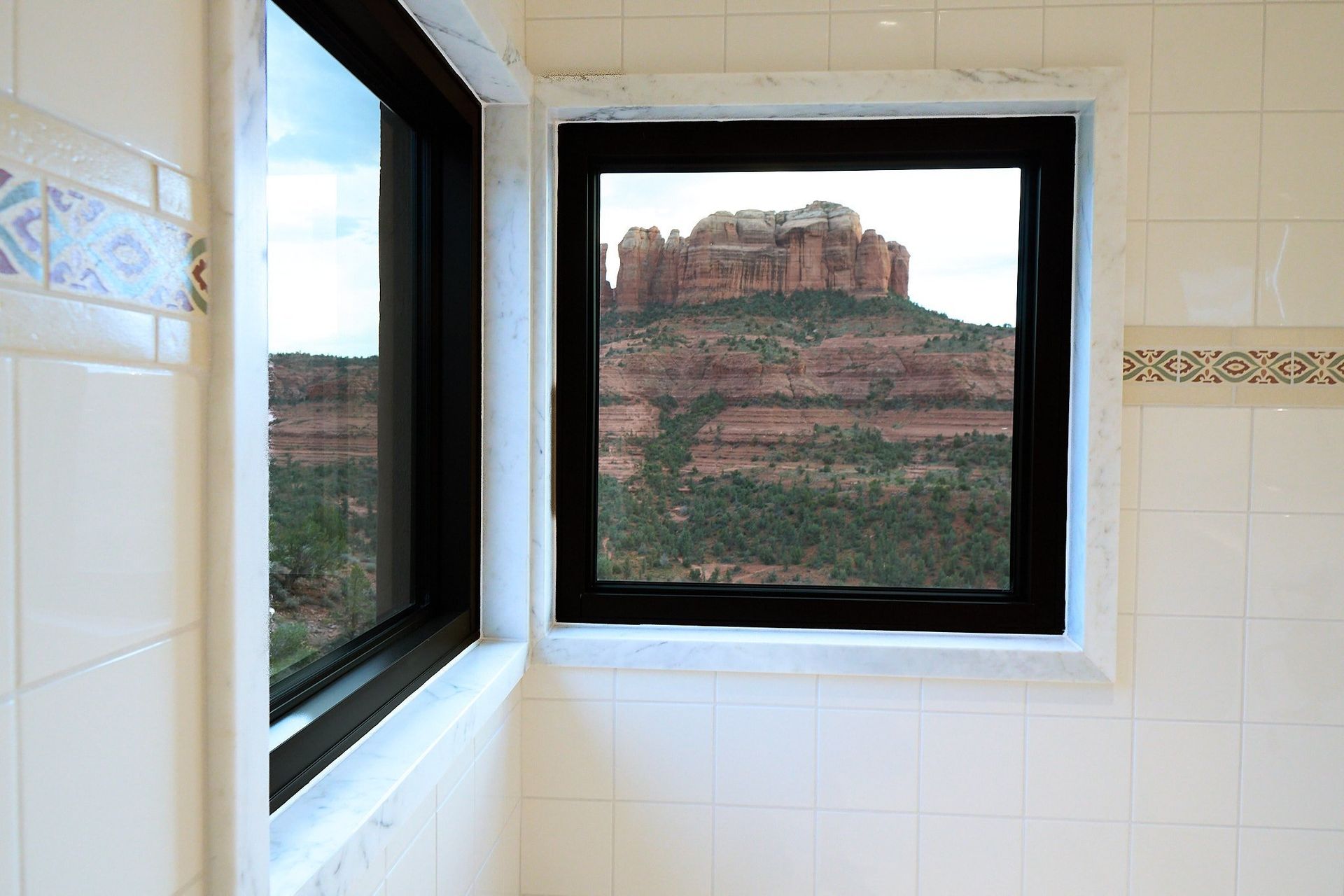 A bathroom window with a view of a mountain.