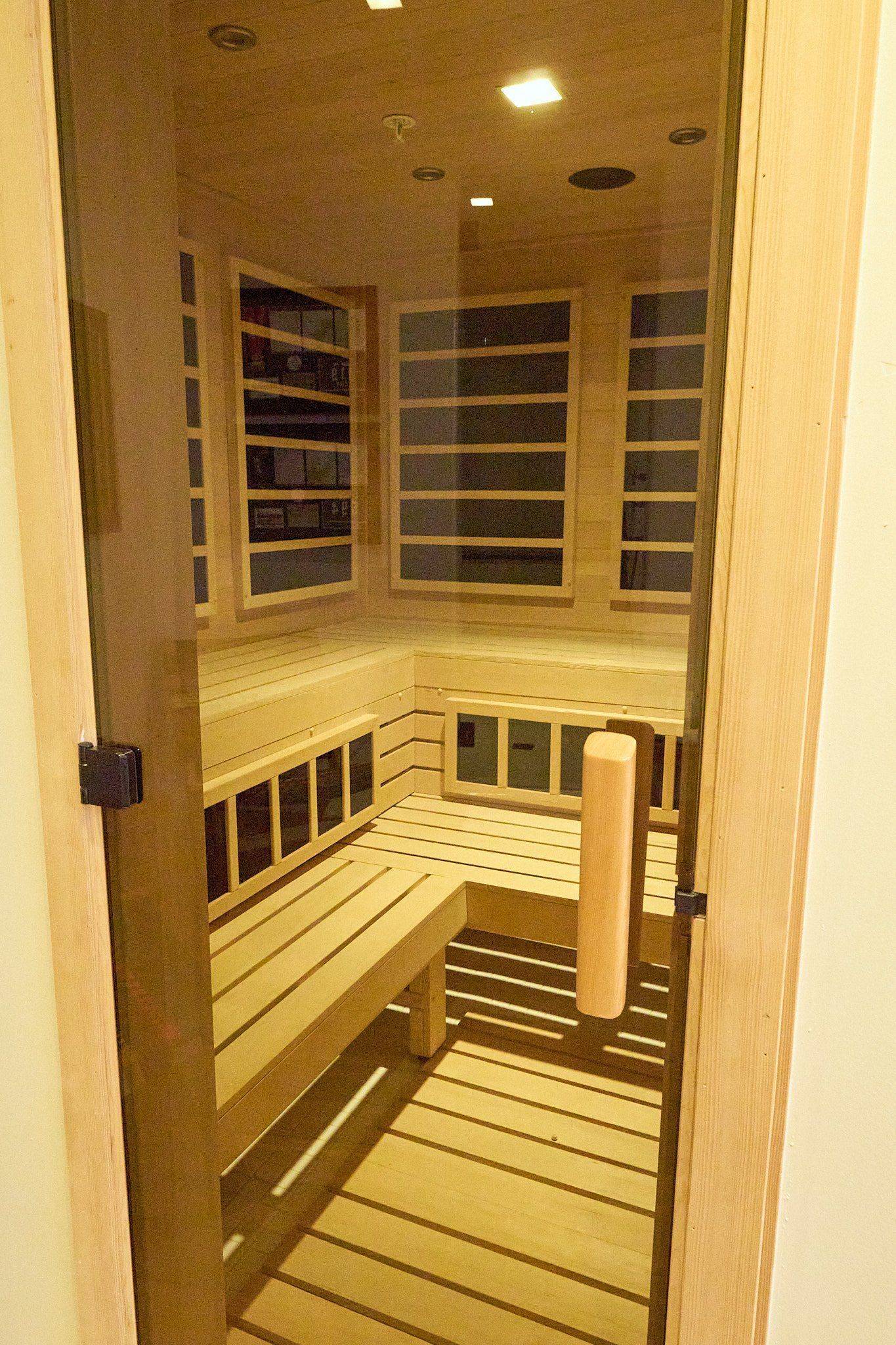 A wooden sauna with a glass door and a wooden bench.