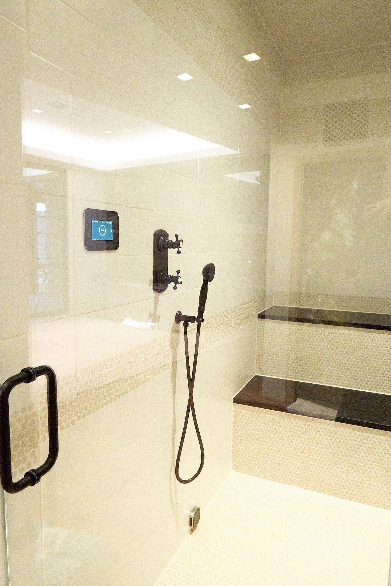A bathroom with a shower and a thermostat on the wall.